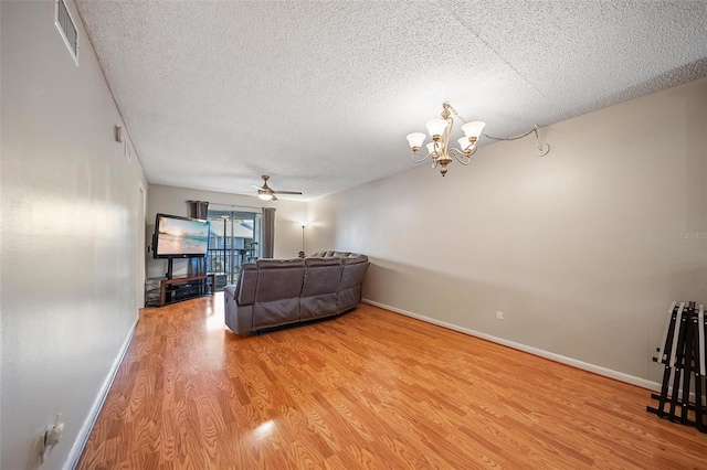 6033 34th St W Unit 132, Bradenton, FL 34210 - living room featuring a textured ceiling, light wood-type flooring, a chandelier, ceiling fan, and baseboards