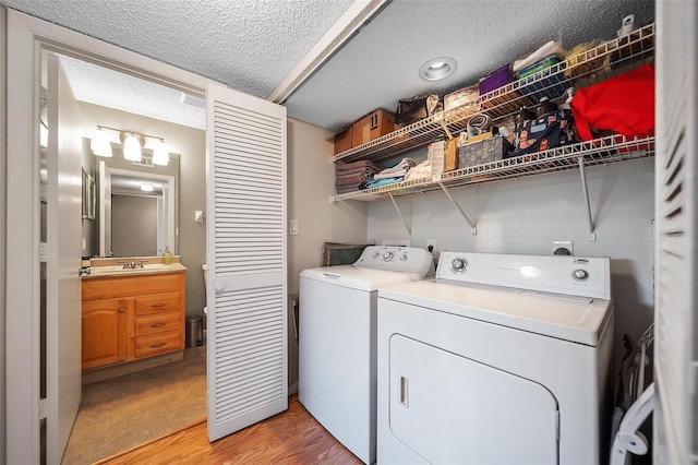 6033 34th St W Unit 132, Bradenton, FL 34210 - laundry room featuring washing machine and clothes dryer, a sink, light wood finished floors, and a textured ceiling