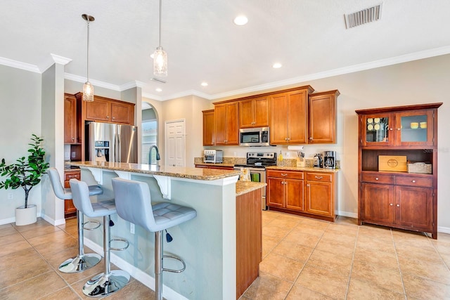 6729 45th Ter E, Bradenton, FL 34203 - kitchen with visible vents, appliances with stainless steel finishes, a kitchen breakfast bar, brown cabinets, and light stone countertops