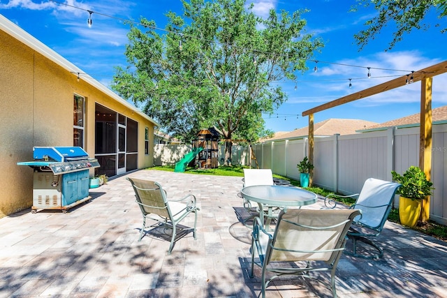 6729 45th Ter E, Bradenton, FL 34203 - view of patio / terrace with a grill, a sunroom, a fenced backyard, a playground, and outdoor dining area