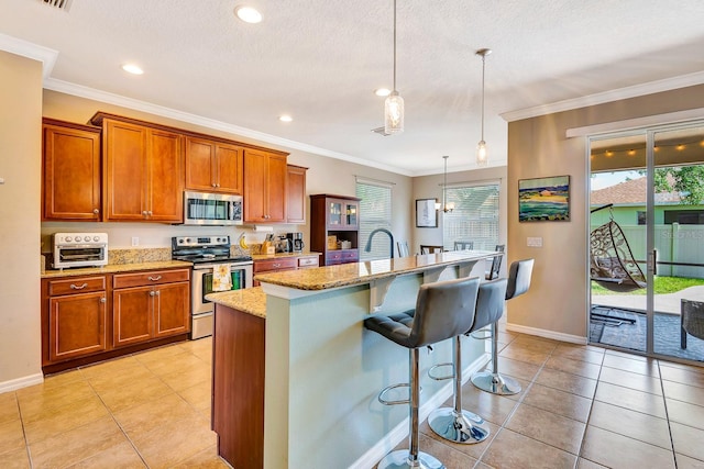 6729 45th Ter E, Bradenton, FL 34203 - kitchen featuring a breakfast bar, light tile patterned floors, a center island with sink, brown cabinetry, and appliances with stainless steel finishes