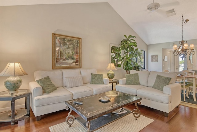 living area with visible vents, a chandelier, high vaulted ceiling, and dark wood-type flooring