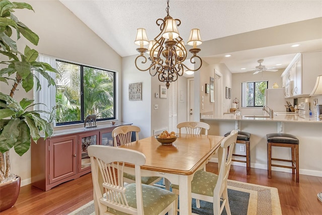 dining space with a textured ceiling, vaulted ceiling, recessed lighting, a chandelier, and light wood-style floors