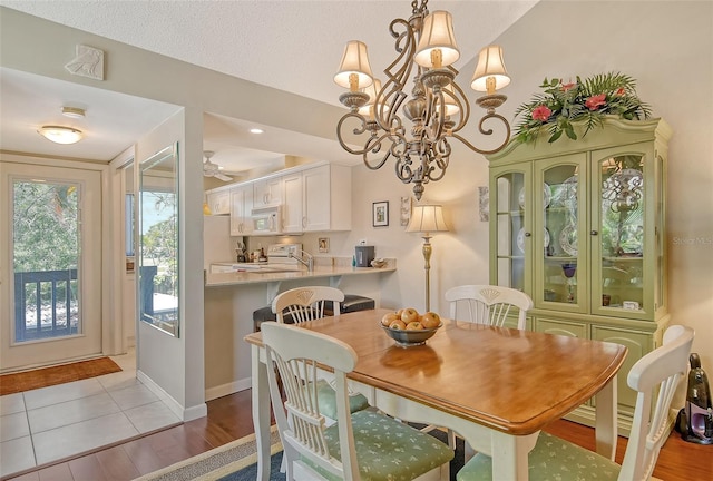 dining room with light wood finished floors, baseboards, and ceiling fan with notable chandelier