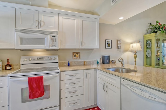 kitchen featuring visible vents, a sink, white appliances, light stone countertops, and white cabinetry