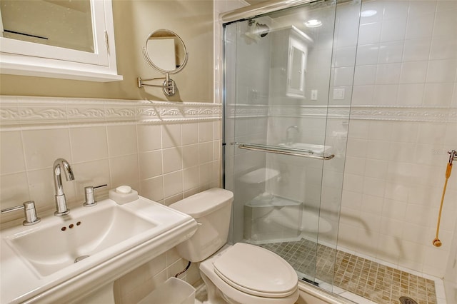 full bathroom with tile walls, toilet, a stall shower, and a sink