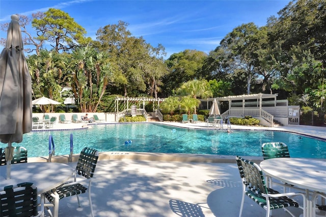 community pool with a pergola, a patio area, and fence