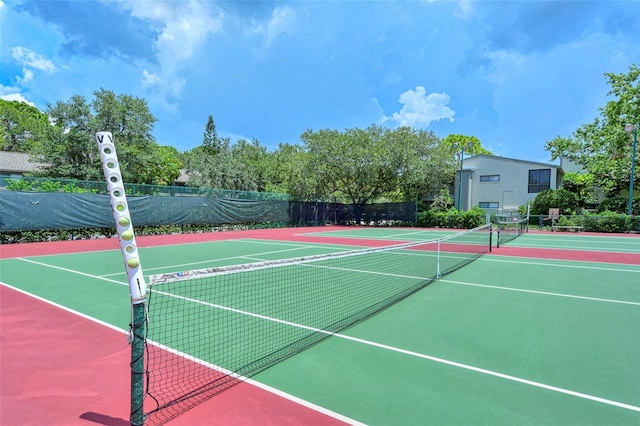 view of tennis court with community basketball court and fence
