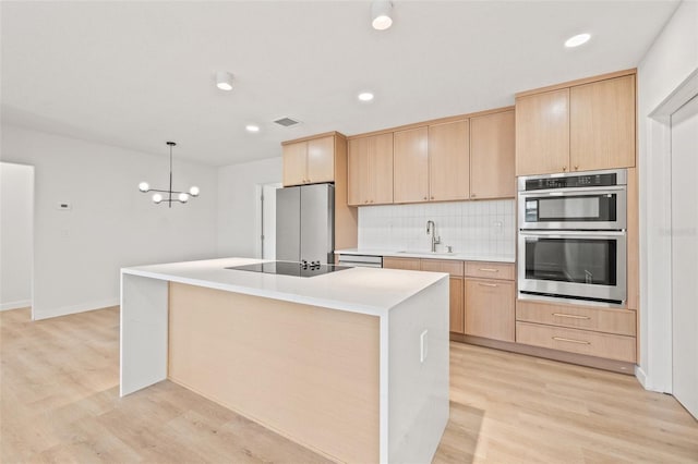 1050 55th Ave S, Saint Petersburg, FL 33705 - kitchen with a sink, light brown cabinetry, stainless steel appliances, light wood-type flooring, and decorative backsplash