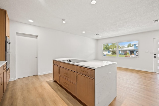 1050 55th Ave S, Saint Petersburg, FL 33705 - kitchen with light wood finished floors, light countertops, a center island, a textured ceiling, and recessed lighting
