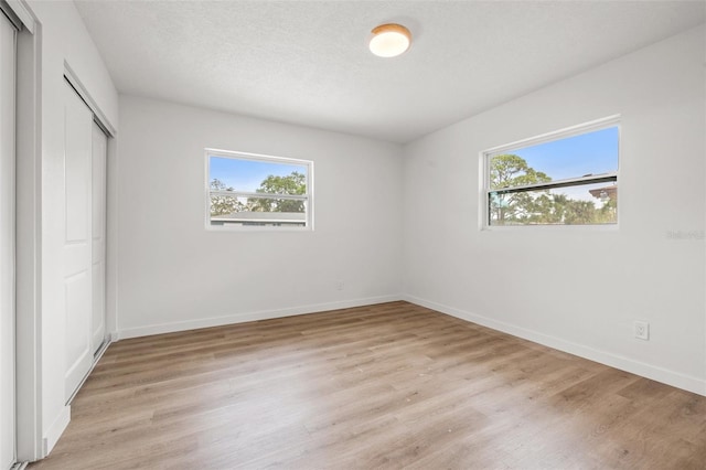 1050 55th Ave S, Saint Petersburg, FL 33705 - unfurnished bedroom featuring multiple windows, light wood-style floors, a closet, and baseboards