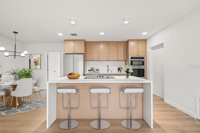 1050 55th Ave S, Saint Petersburg, FL 33705 - kitchen featuring stainless steel appliances, a kitchen breakfast bar, backsplash, light countertops, and recessed lighting