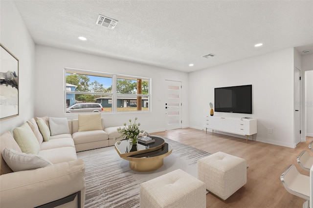 1050 55th Ave S, Saint Petersburg, FL 33705 - living room featuring light wood-style floors, recessed lighting, a textured ceiling, and baseboards