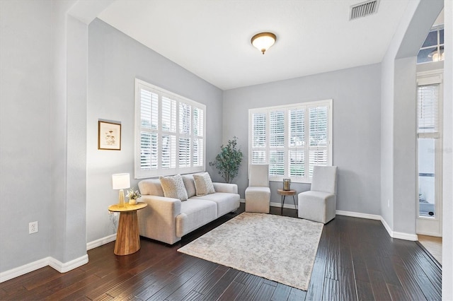 living room featuring dark wood-style flooring, baseboards, and visible vents