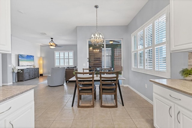 dining area with ceiling fan with notable chandelier, light tile patterned floors, and baseboards