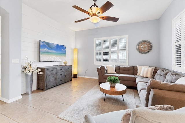living area featuring light tile patterned floors, ceiling fan, baseboards, and a wealth of natural light