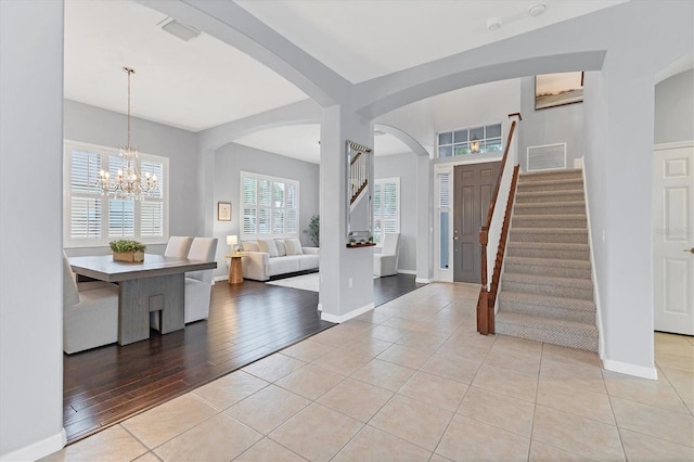 foyer featuring light tile patterned floors, a notable chandelier, visible vents, and stairs