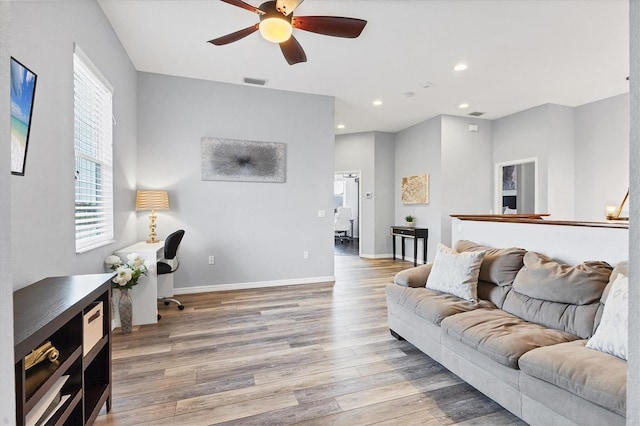 living area featuring a healthy amount of sunlight, visible vents, a ceiling fan, and wood finished floors