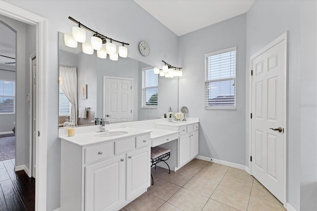 bathroom with tile patterned floors, double vanity, a sink, and baseboards