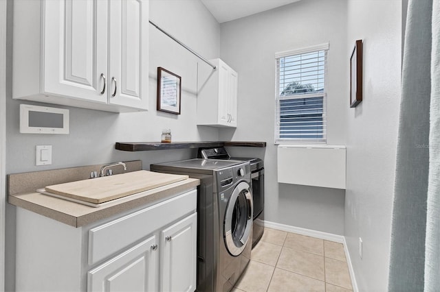 laundry area featuring cabinet space, light tile patterned floors, independent washer and dryer, and baseboards