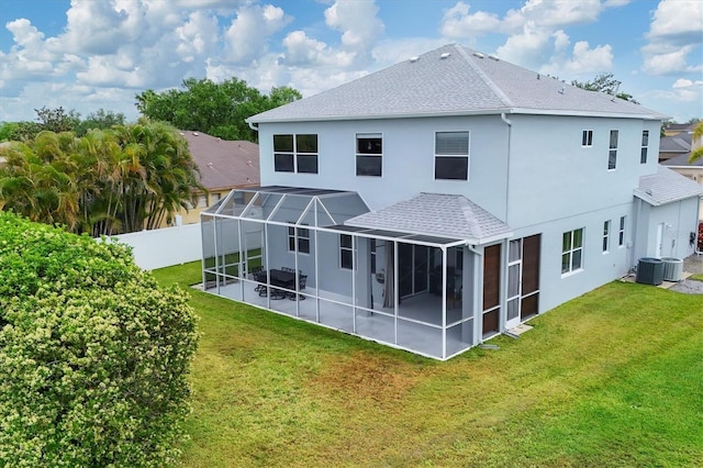 back of property featuring a yard, stucco siding, fence, and glass enclosure