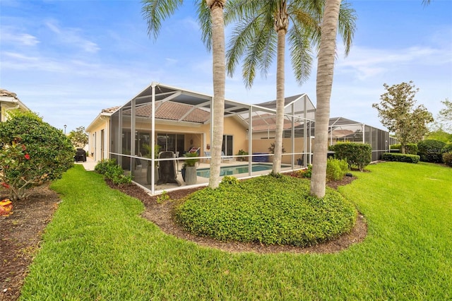 rear view of house with a yard, an outdoor pool, stucco siding, and glass enclosure