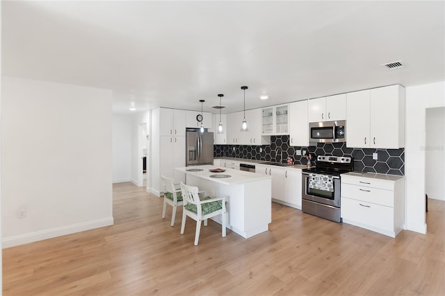 kitchen featuring visible vents, a center island, appliances with stainless steel finishes, a breakfast bar area, and backsplash