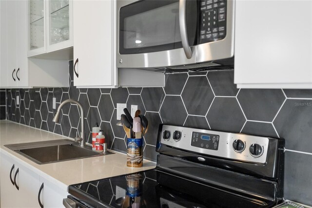 kitchen with tasteful backsplash, a sink, white cabinets, and stainless steel appliances