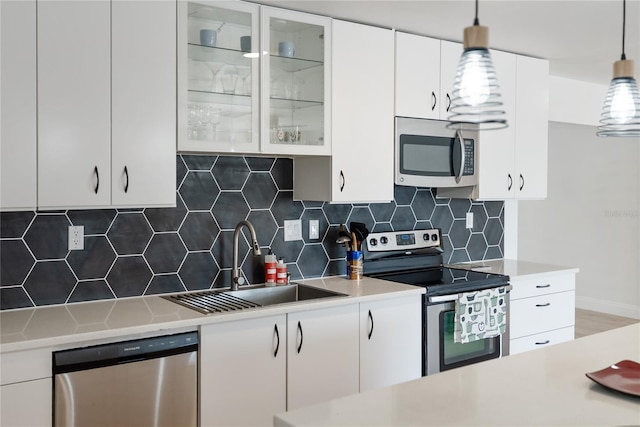 kitchen featuring stainless steel appliances, light countertops, a sink, and white cabinetry