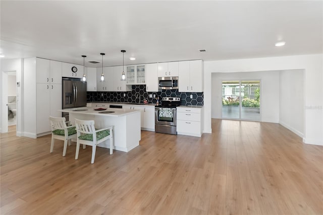 kitchen with tasteful backsplash, a breakfast bar, a kitchen island, stainless steel appliances, and hanging light fixtures