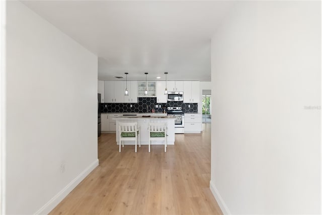 kitchen with a kitchen bar, white cabinets, appliances with stainless steel finishes, decorative backsplash, and baseboards