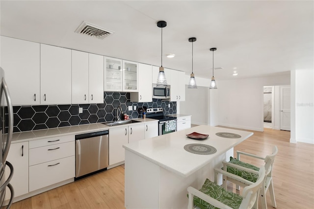 kitchen featuring light countertops, visible vents, a kitchen bar, stainless steel appliances, and a sink