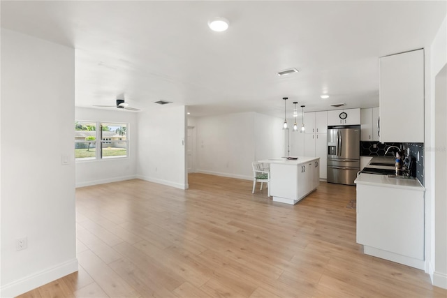 kitchen with stainless steel fridge with ice dispenser, open floor plan, and baseboards