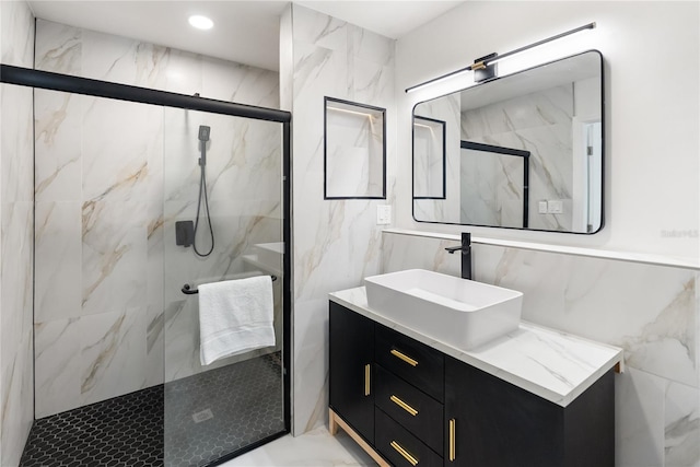 bathroom with marble finish floor, a marble finish shower, vanity, and tile walls
