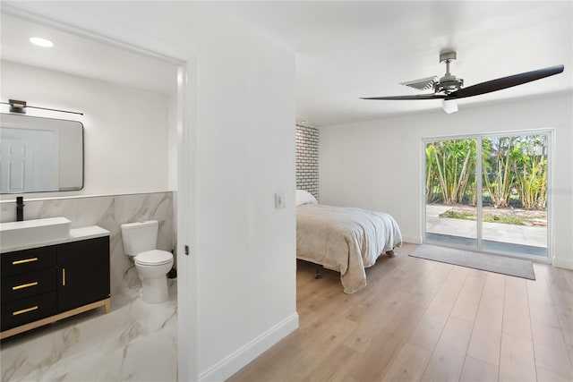 bedroom with baseboards, ensuite bathroom, access to exterior, and a sink