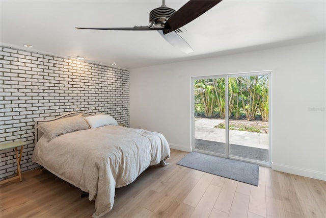 bedroom featuring light wood-type flooring, a ceiling fan, access to exterior, brick wall, and baseboards