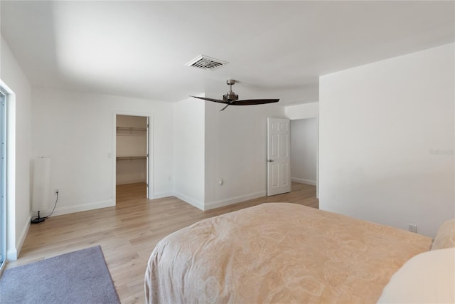 bedroom with baseboards, a spacious closet, light wood-style floors, visible vents, and ceiling fan