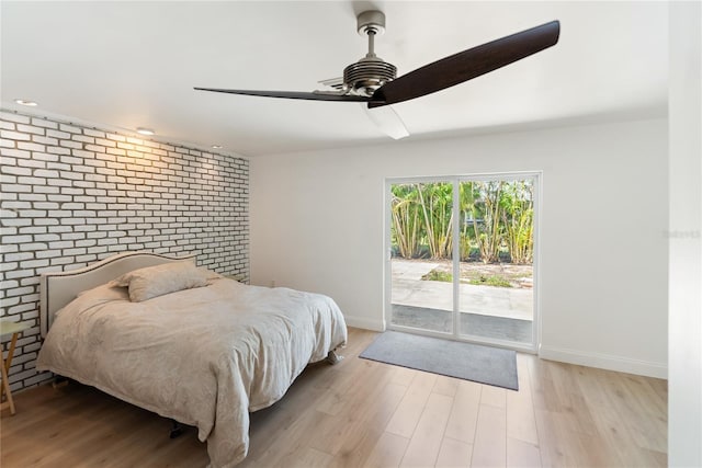bedroom featuring a ceiling fan, access to exterior, wood finished floors, brick wall, and baseboards