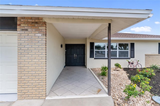 entrance to property with stucco siding and a shingled roof