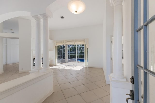 entryway with arched walkways, light tile patterned floors, visible vents, and ornate columns