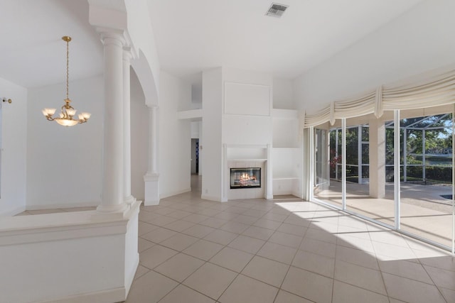 unfurnished living room featuring a tiled fireplace, visible vents, arched walkways, and light tile patterned flooring