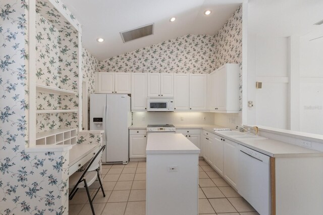 kitchen with wallpapered walls, vaulted ceiling, white appliances, visible vents, and a sink
