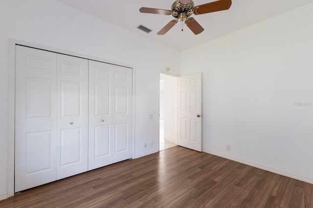 unfurnished bedroom featuring visible vents, baseboards, a closet, and wood finished floors