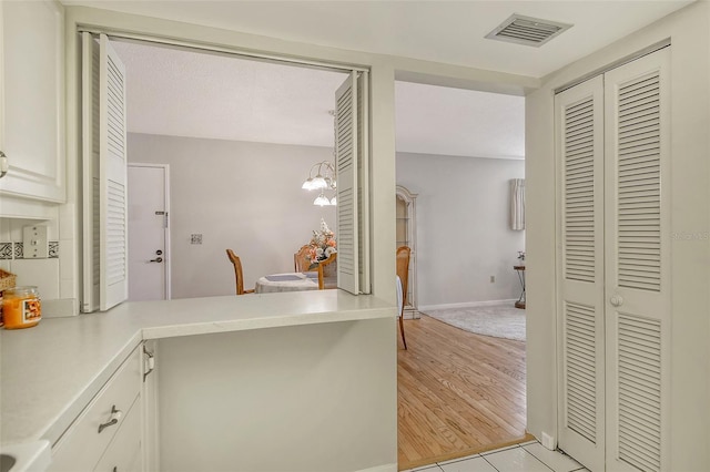 1532 Pelican Point Dr Unit Ba139, Sarasota, FL 34231 - kitchen featuring visible vents, light countertops, baseboards, light wood finished floors, and a peninsula