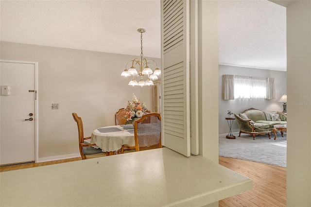 1532 Pelican Point Dr Unit Ba139, Sarasota, FL 34231 - dining area featuring baseboards, wood finished floors, a notable chandelier, and a textured ceiling