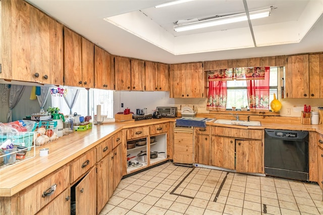 kitchen with a toaster, light tile patterned flooring, a tray ceiling, a sink, and dishwasher