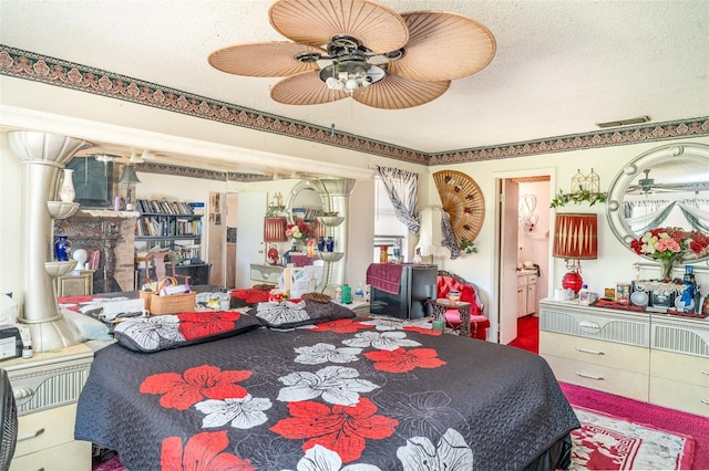 bedroom with ceiling fan, ensuite bath, a textured ceiling, and visible vents