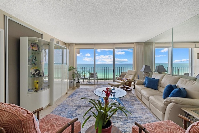living room featuring a textured ceiling, light tile patterned floors, and a water view