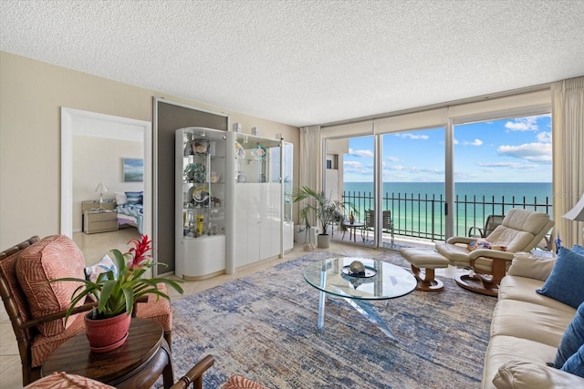 living area with floor to ceiling windows, a textured ceiling, and a water view