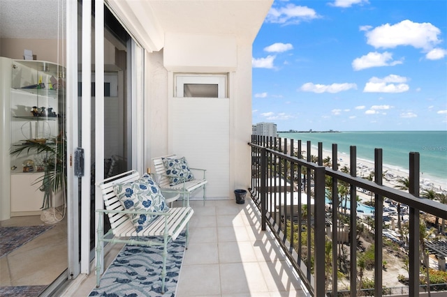 balcony featuring a view of the beach and a water view